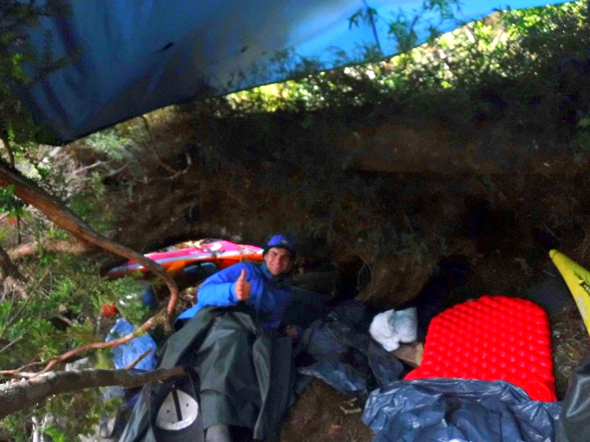 George Bull giving a thumbs up from the Hobbit Hole, a tarp shelter on Isla Marina Jarpa in Chilean Patagonia.